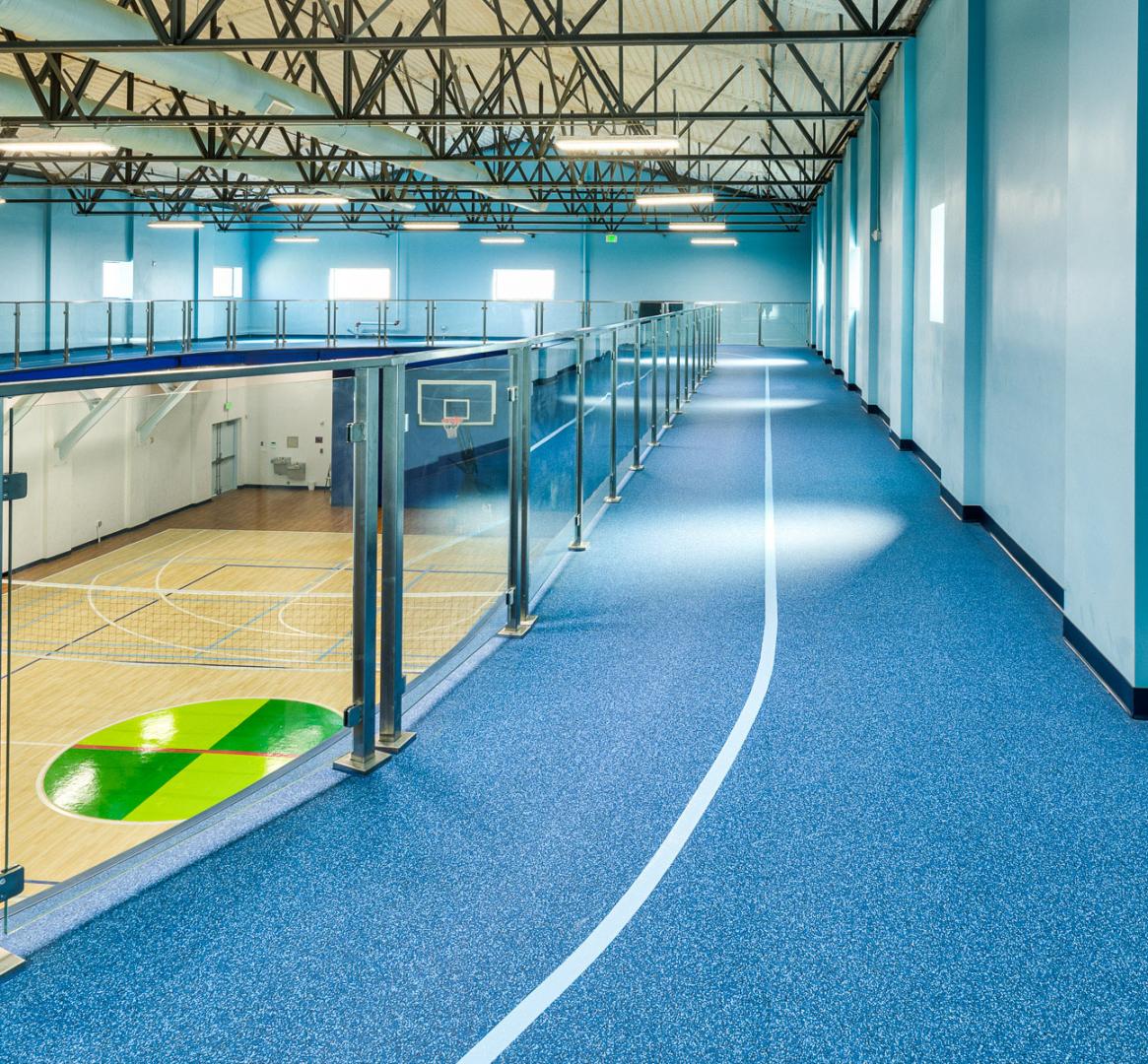 Overhead view of an indoor sports complex featuring a basketball court and running track.