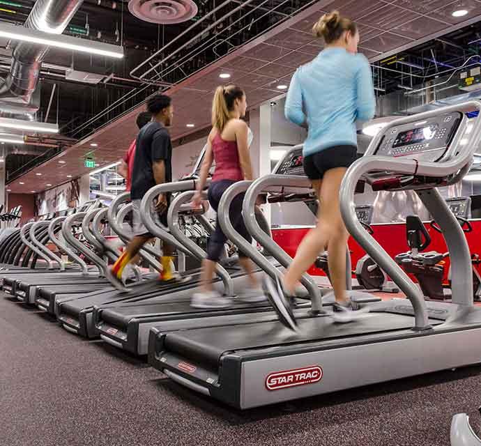 Group of people running on treadmills in a modern gym.