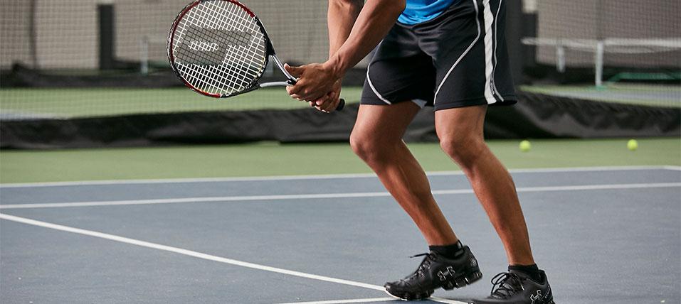 Tennis player standing ready with a tennis racket on a tennis court. 