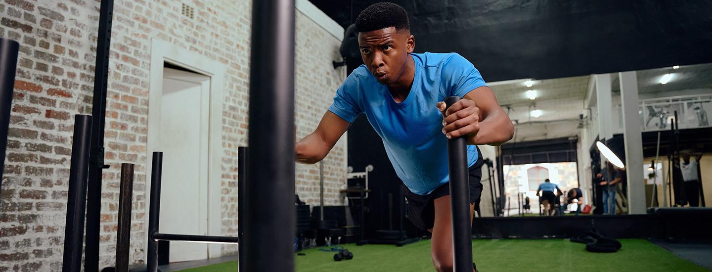 Focused man pushing a heavy sled in a functional fitness gym.