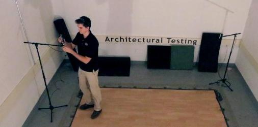 Man conducting architectural testing with sound equipment in a lab setting.