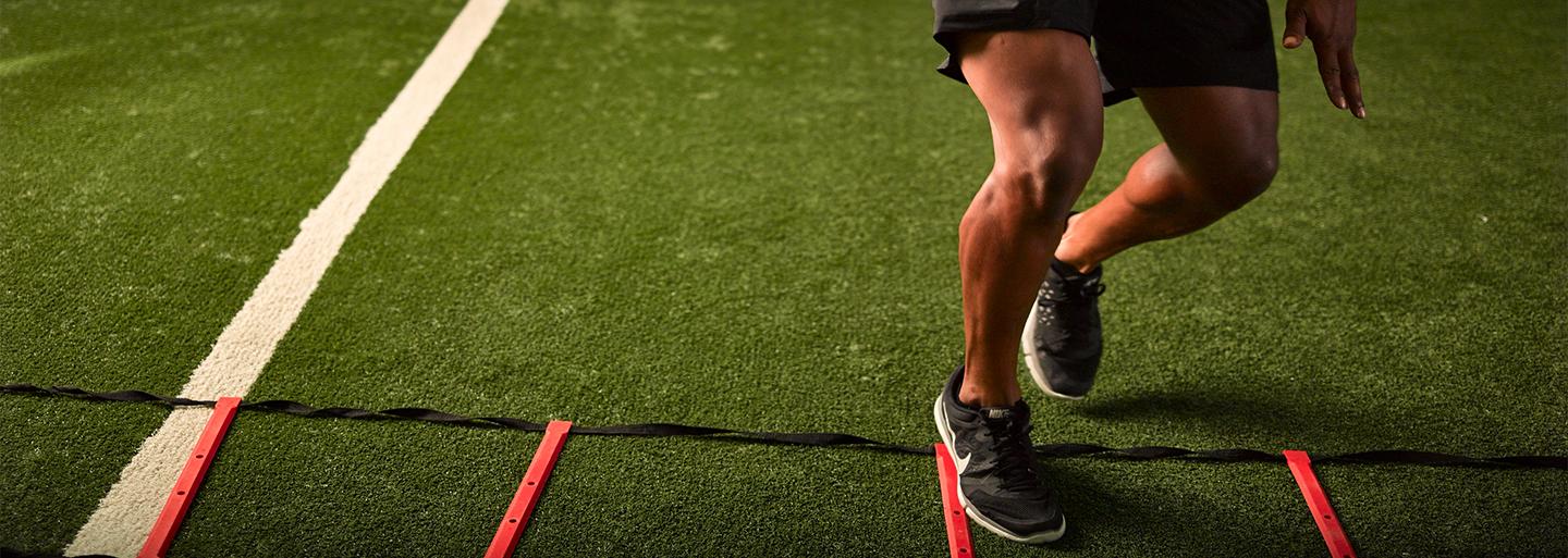 An athlete doing a speed and agility drill with a ladder on Ecore turf