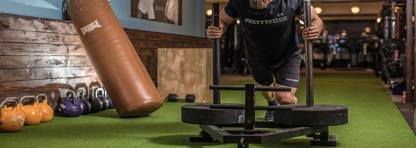 A man performing a functional training exercise and pushing a sled