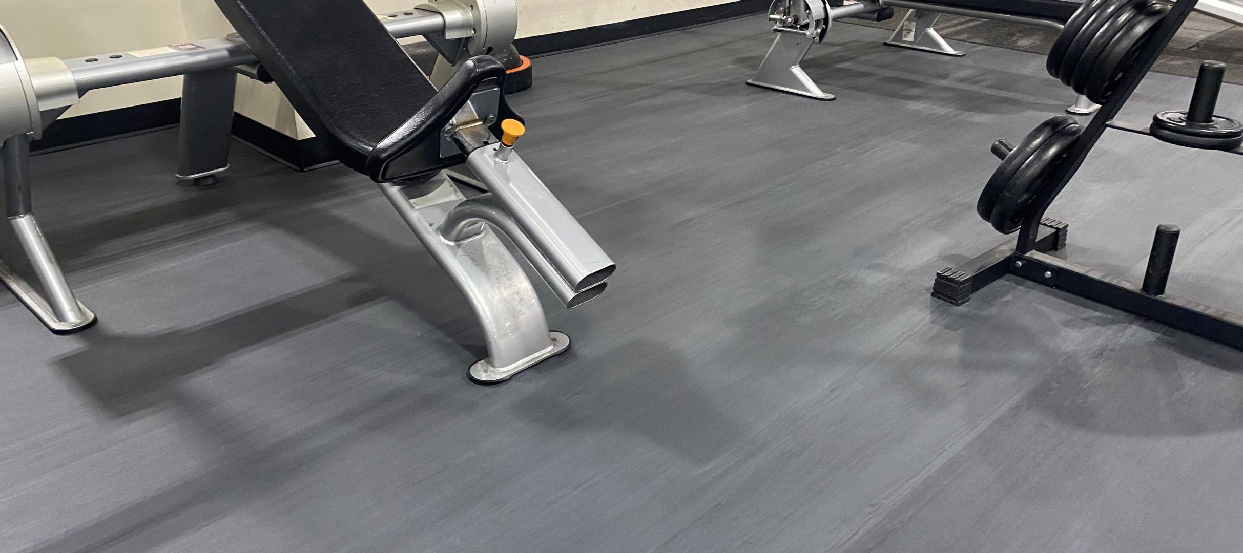 Adjustable gym benches near a barbell setup in a fitness space.