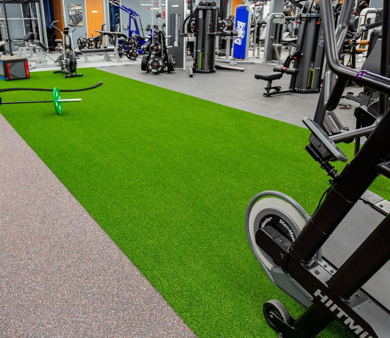 A gym featuring a vibrant green FlexTurf floor, designed for various athletic activities and workouts.