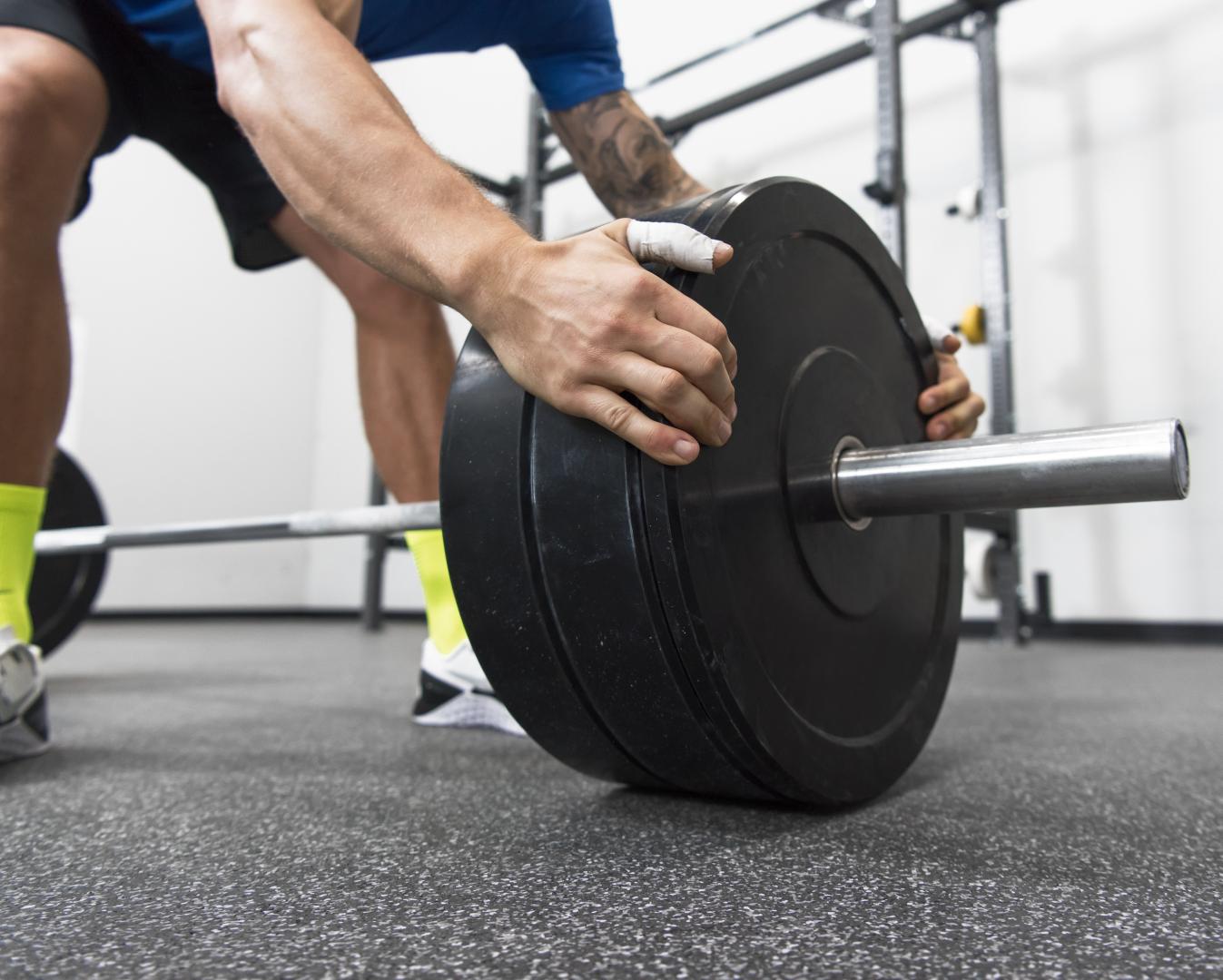 Man loading a barbell with weights getting ready for his next lift