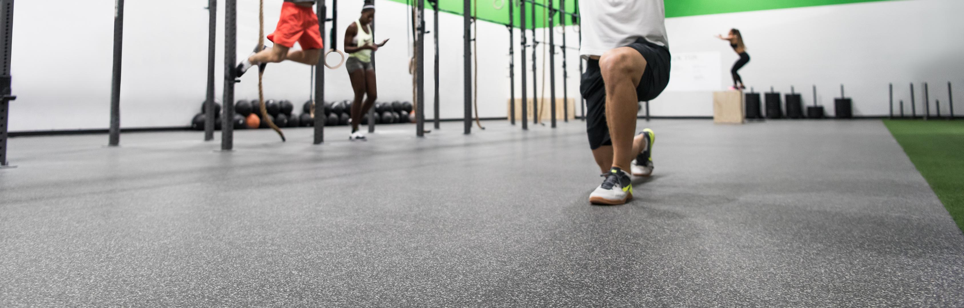 Man doing lunches on performance motivate plus flooring in fitness center or gym