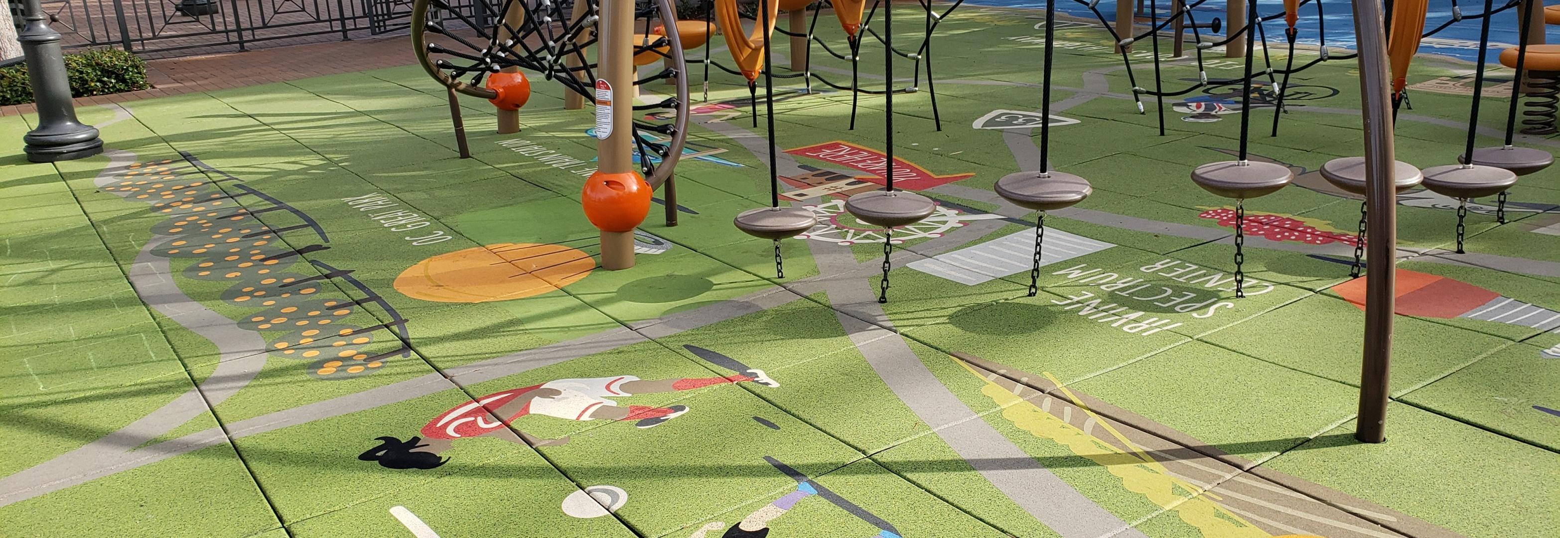 A playground with a very colorful and detailed floor that is made up of PlayGuard Tiles