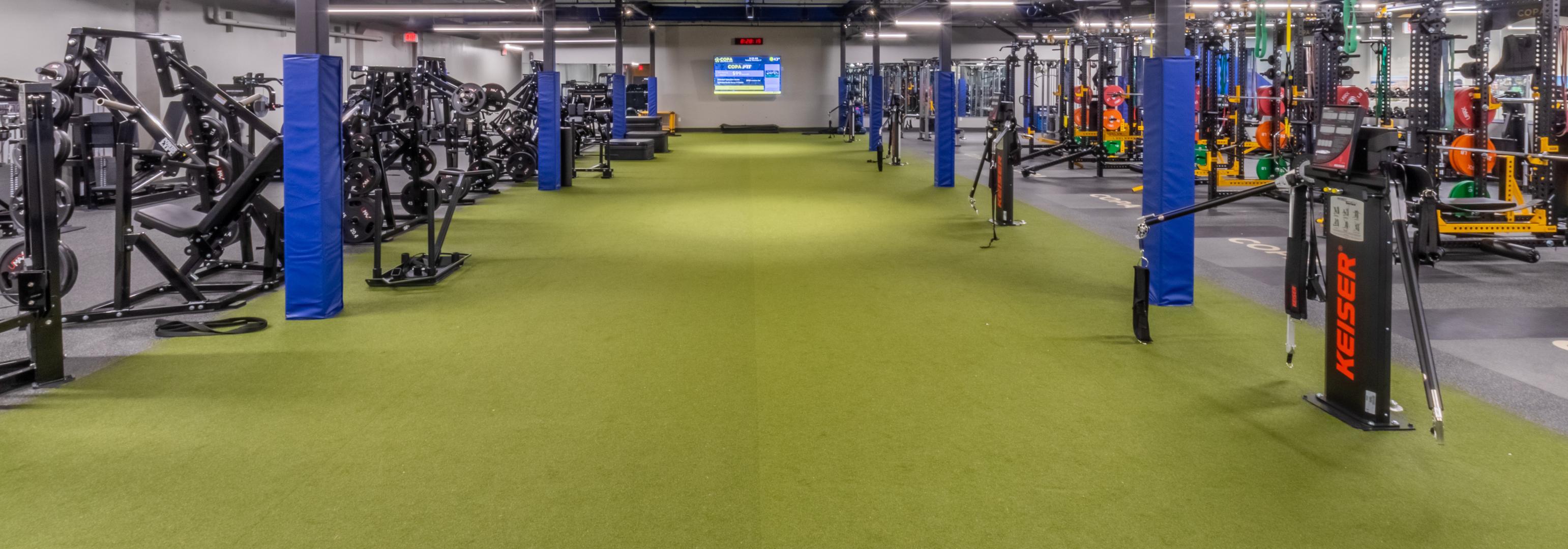 A gym environment showcasing a green RageTurf floor and multiple pieces of exercise equipment.