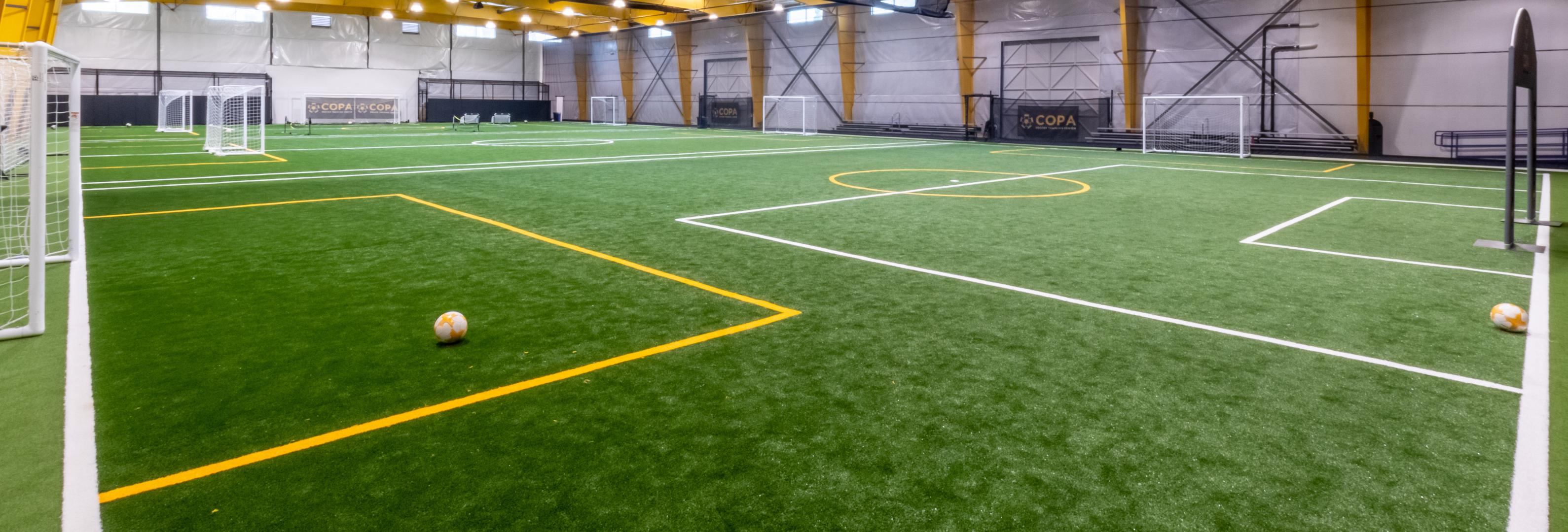 A filed house with multiple soccer turf fields with soccer balls and FlexTurf Monster installed