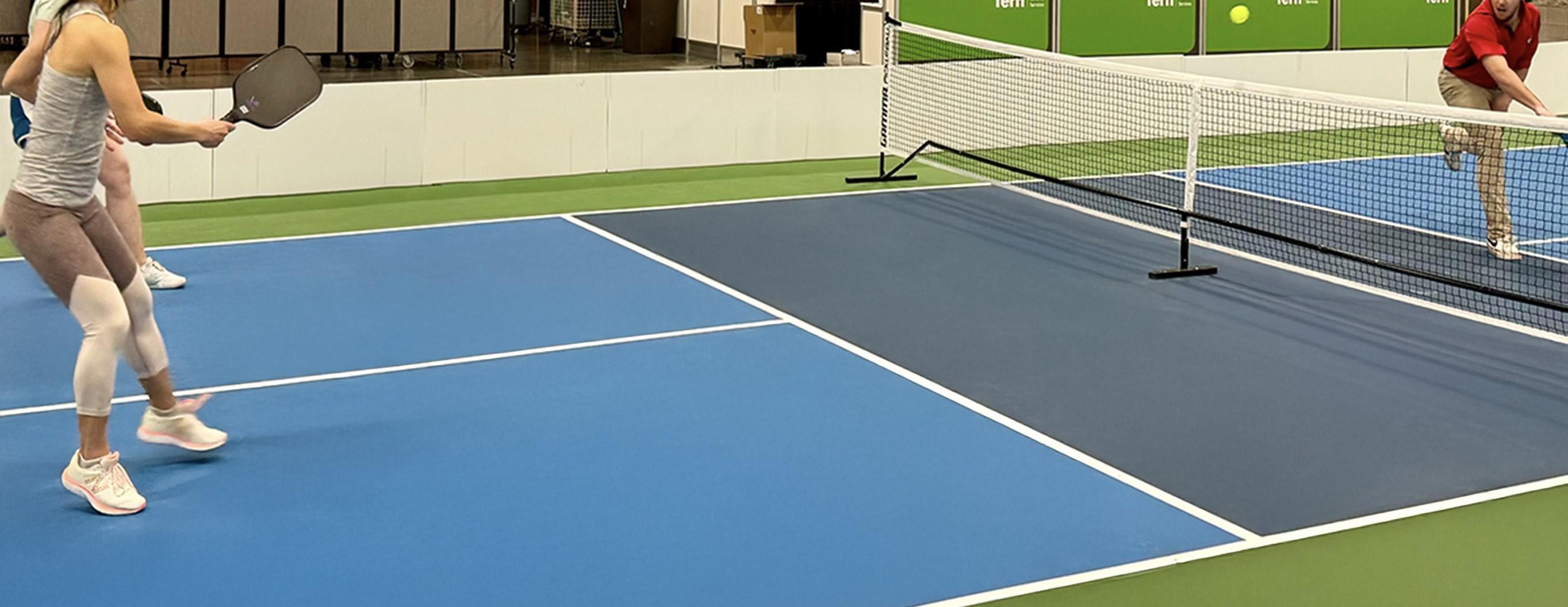 Two adults playing an intense game of pickleball on a MODcourt Pickle court