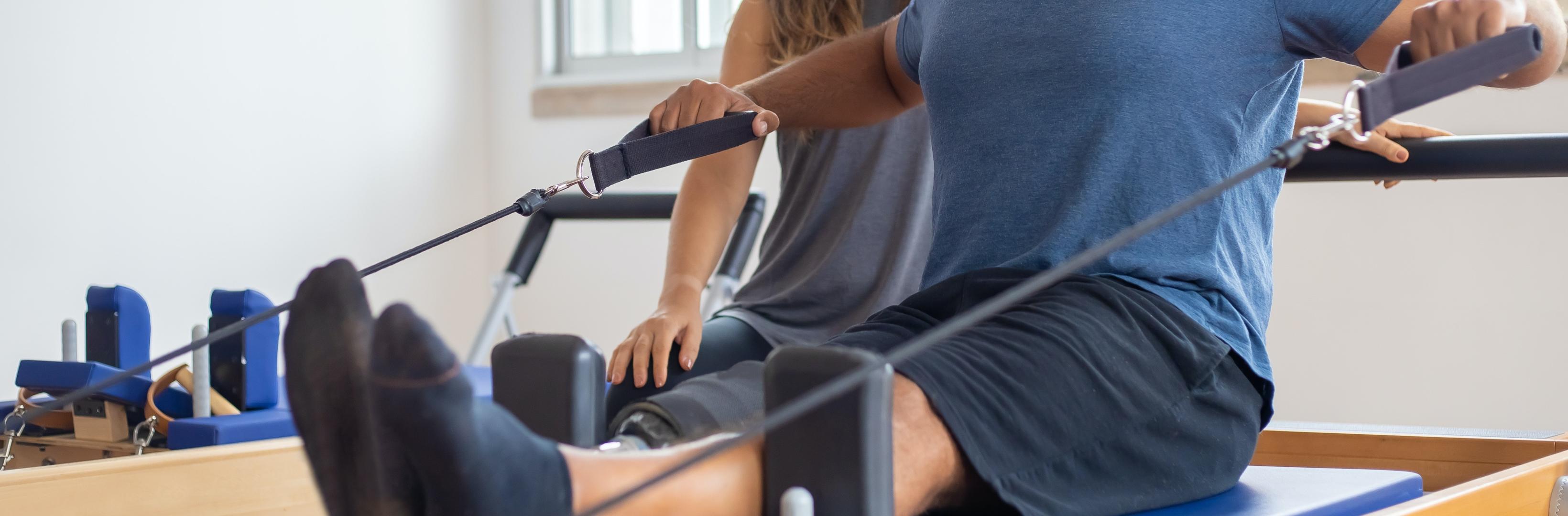 A man doing a physical therapy exercise while a woman is helping him out