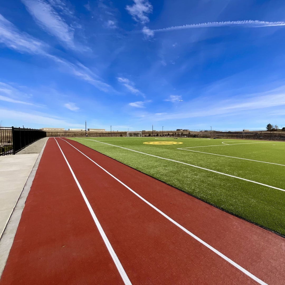 A OSSTrax Track with a green turf field to the right and a very blue sky