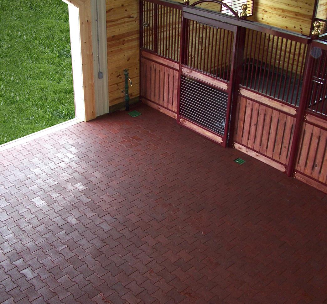 Paved walkway lined with hedges and a white fence leading to a gate.