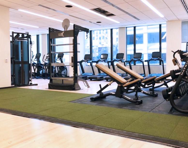 A fitness facility with different pieces of equipment and turf in the middle