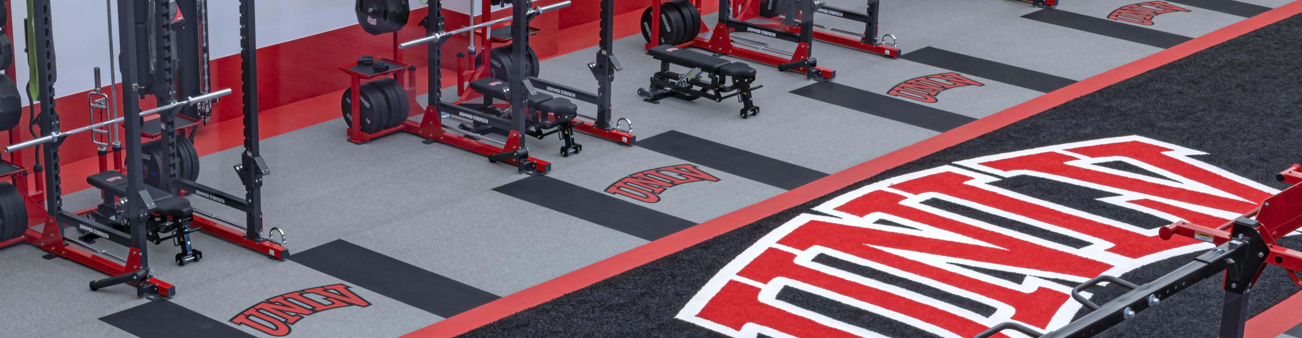 A line of lifting platforms at a training facility with college logos in the platform