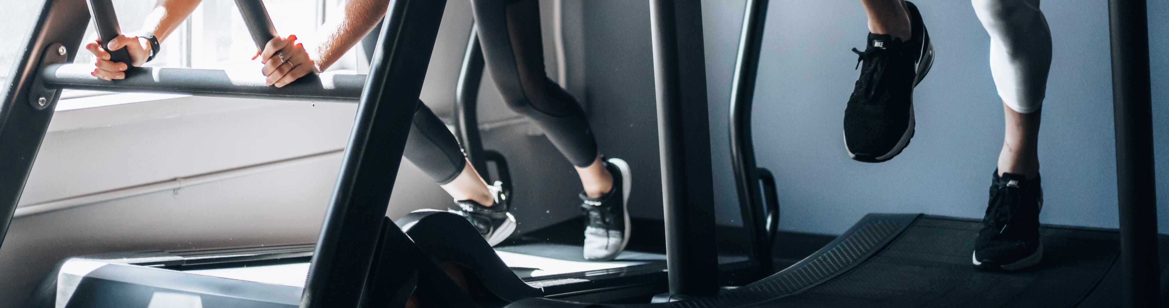 Two athletes both using cardio machines