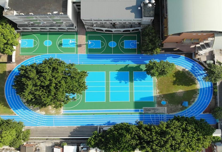 An overhead shot of a blue colorful OSSTrax Elite track with trees and courts surrounding it