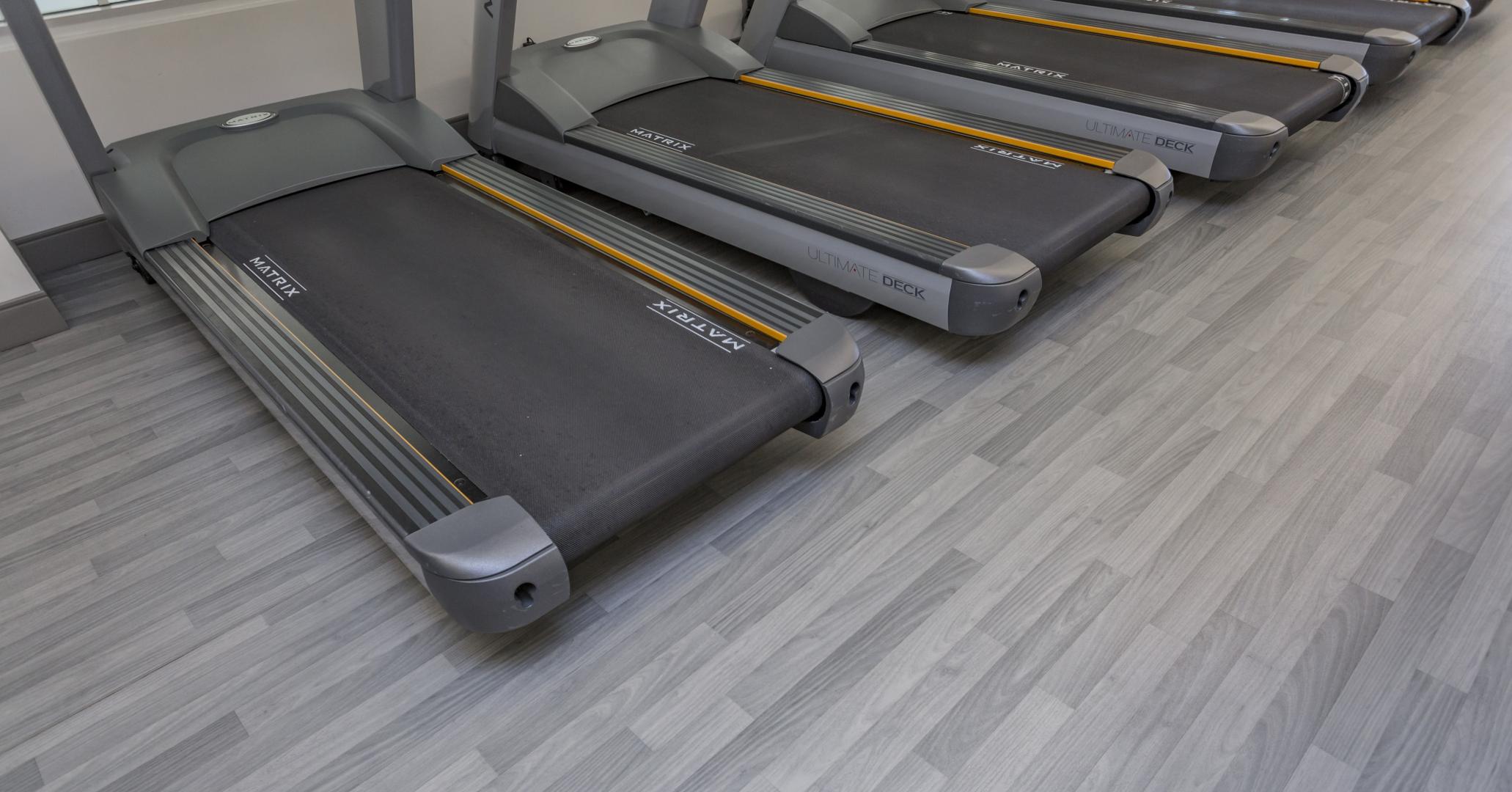 A line of treadmills close up on a vinyl floor