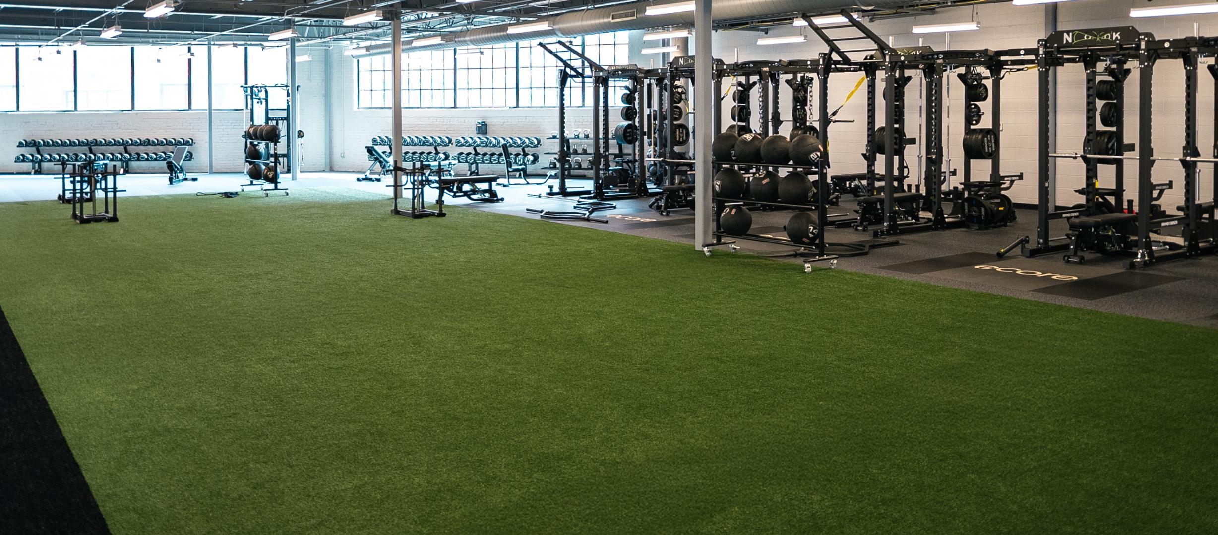 A gym with a section of turf installed in the middle with a sled on it