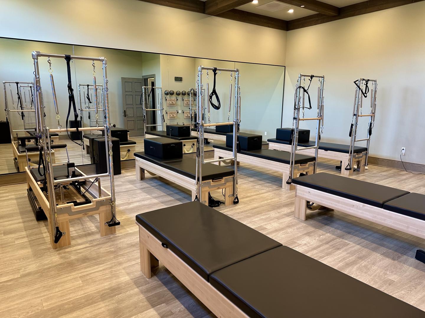 A pilates studio with many pieces of equipment and Ecore Athletic flooring