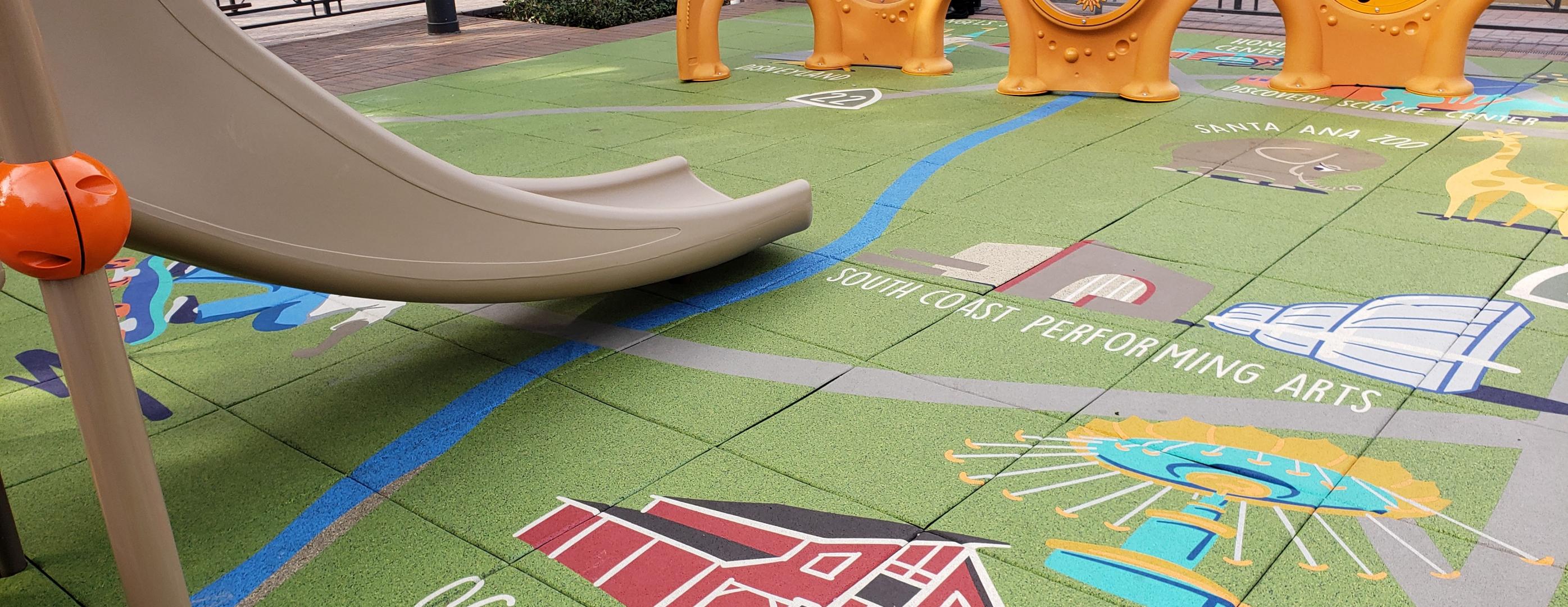Colorful playground rubber flooring with illustrations and a gray slide.