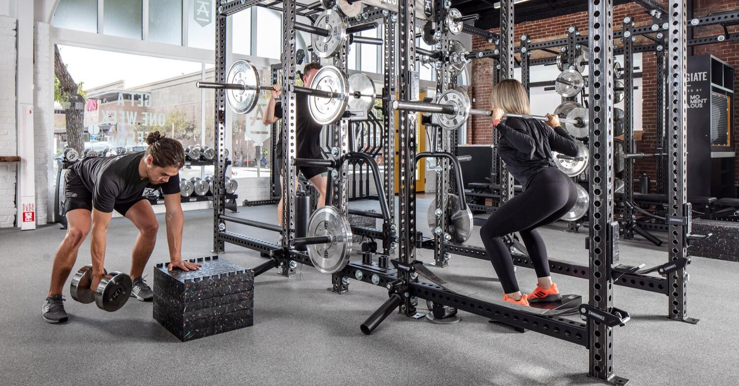 Well-equipped gym with weights and fitness equipment on a grey floor.
