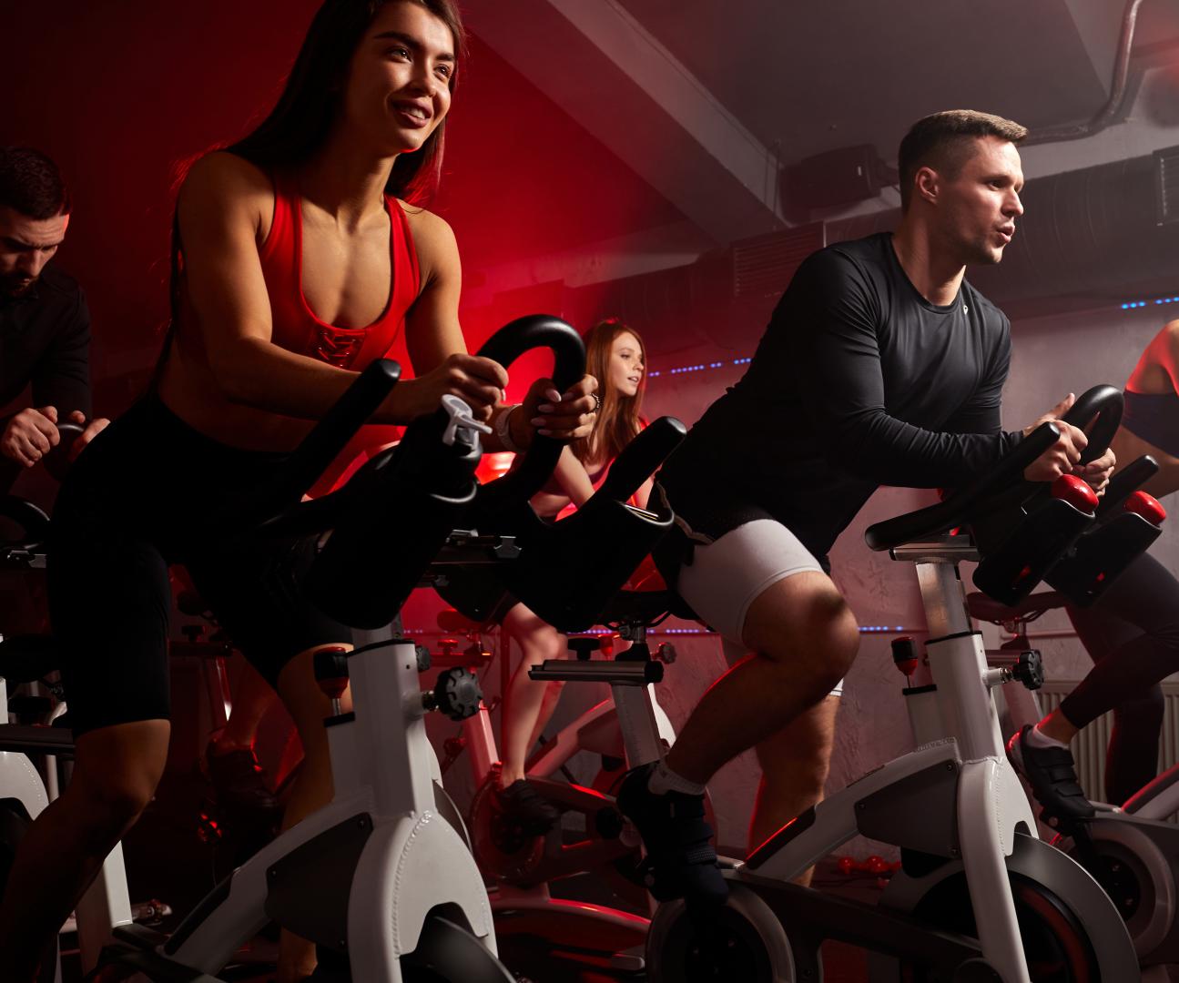 A man and woman are engaged in a workout, running on adjacent treadmills in a fitness center.