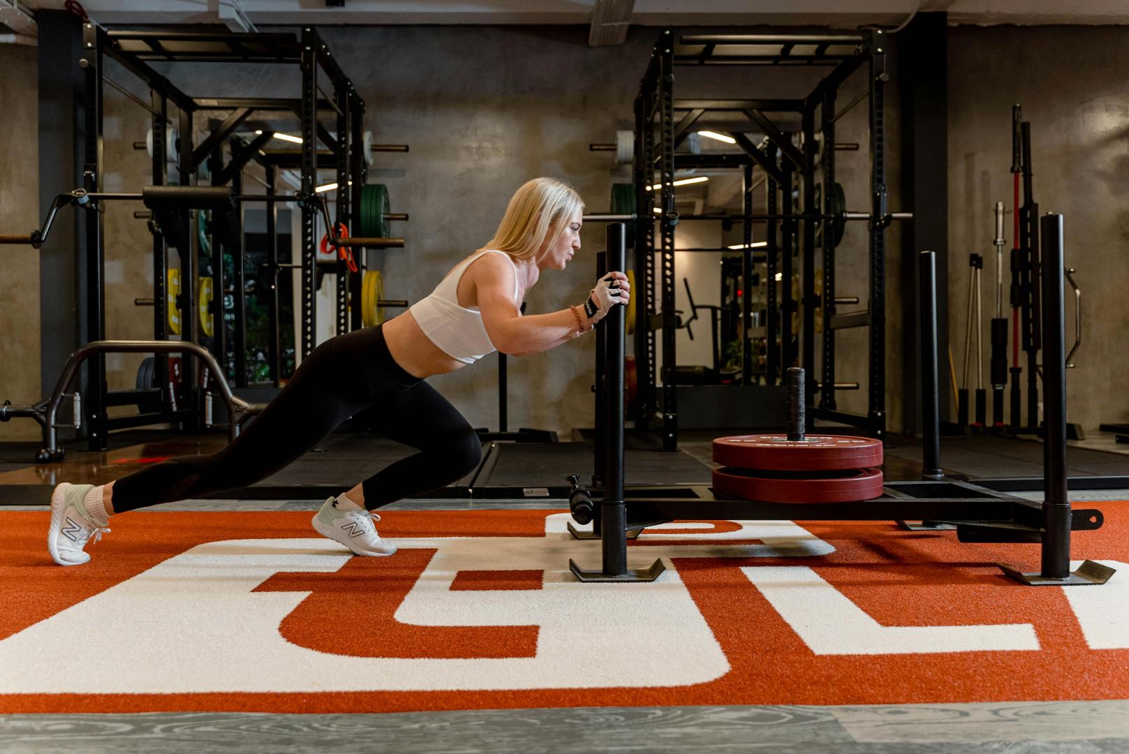 A women pushing a sled on RageTurf NIL