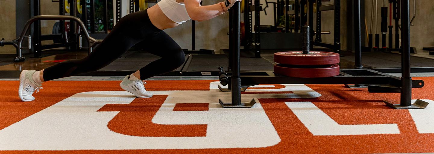 A women pushing a sled on RageTurf NIL